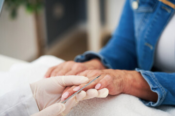 Senior lady wearing a mask in manicure salon