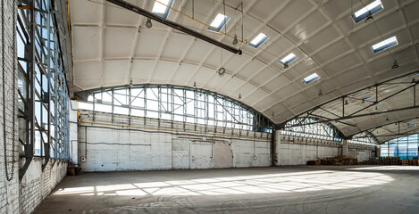 Corner of huge empty industrial warehouse. Modern building hemispherical reinforced concrete load bearing roof. Metal construction. Wooden pallets.