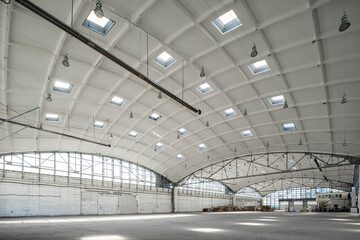 Huge industrial warehouse. White interior. Hemispherical reinforced concrete load bearing roof with windows. Modern architecture. Wooden pallets.