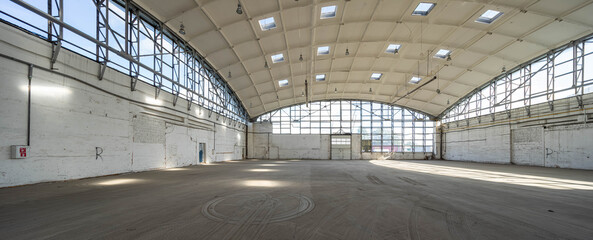 Huge empty industrial warehouse. White interior. Unique architecture. Hemispherical reinforced concrete load bearing roof with windows. Modern building.