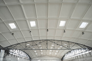 Hemispherical reinforced concrete load bearing roof with windows in huge industrial warehouse. White interior. Unique soviet architecture.