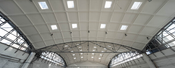 Hemispherical reinforced concrete load bearing roof with windows in huge industrial warehouse. White interior. Unique soviet architecture.