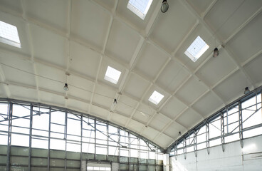 Hemispherical reinforced concrete load bearing roof with windows in huge industrial warehouse. White interior. Unique soviet architecture.