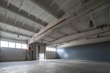 Modern interior of huge empty concrete industrial warehouse. White brick wall.