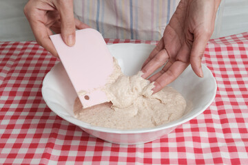 Kneading a dough of bread in a bowl. Female hands working. Making pizza. Cooking at home. Homemade food. Italian cloth.