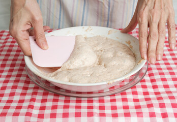 Kneading a dough of bread in a bowl. Female hands working. Making pizza. Cooking at home. Homemade food. Italian cloth.