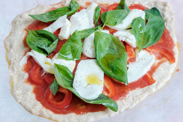 Raw pizza with mozzarella, red peppers, basil and tomato sauce. Ready to bake. Making pizza. Cooking italian food. Homemade. Italian cloth. Healthy food.