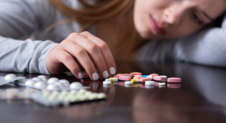 Emotional exhaustion and suicide. Closeup of depressed young lady with pills planning to kill...