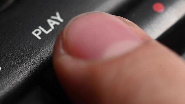 Close-up shallow depth of field. A man's finger presses a button to play on an old tape recorder. Start playing a song
