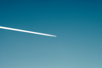 White trail in the sky from a flying plane in frosty weather.
