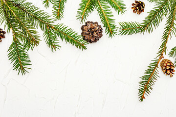 Christmas tree branches with pine cones on white putty background
