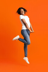 Happy young black woman posing on orange