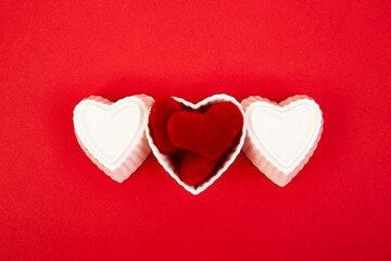 White ceramic hearts with red plush hearts on red background