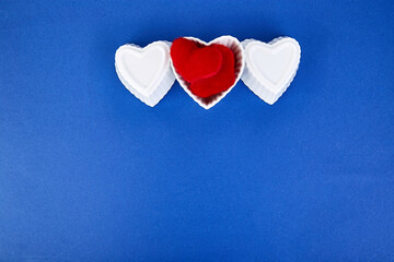 White ceramic hearts with red plush hearts on blue trend color background.