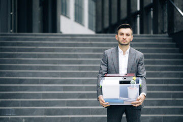 Businessman gets fired and walking near office center with box documents. Lost His Job....