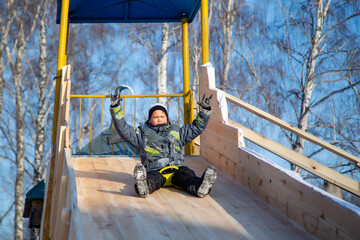 Boy riding a slide on a bright winter day