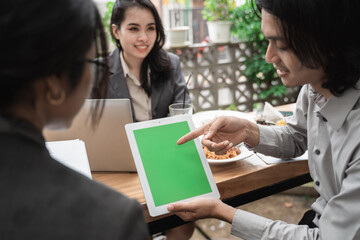 Portrait cheerful of young asian business team meeting in a cafe showing copy space in tablet.