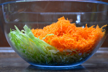 finely chopped cabbage and carrots prepared for salad in a glass bowl