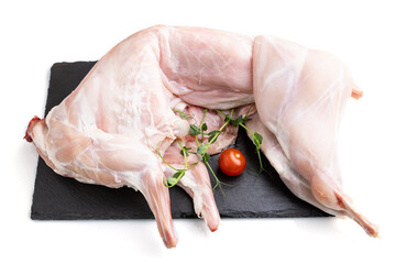 Whole raw rabbit with tomatoes, pea sprouts on a black concrete slate board isolated on white...