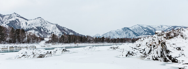 view of the rocks and river at winter. The trees and stones are covered with snow. banner