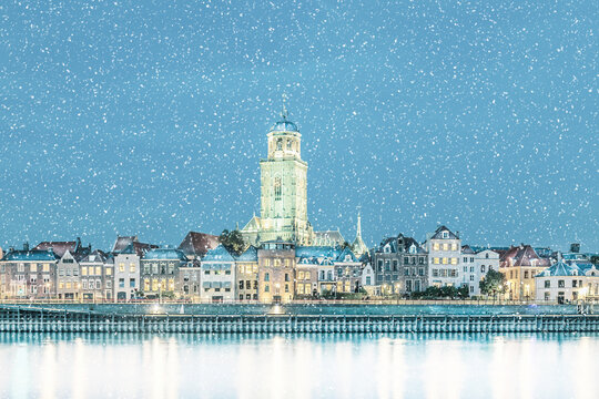 Winter view with snowfall of the Dutch city of Deventer in Overijssel with the river IJssel in front