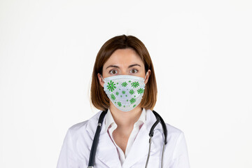 Young female doctor with terrified face wearing mask with corona virus on it isolated on white background. Covid-19 protection concept.