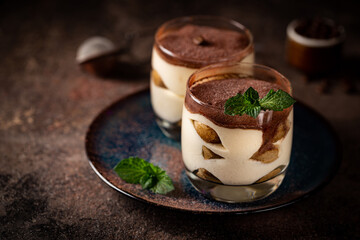 Traditional Italian dessert tiramisu in a glass on on dark background