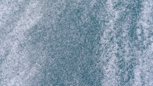 Top view flatlay photography of ice surface of frozen winter river and fresh white snow blowing by wind. Abstract natural winter background.