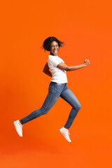 Fototapeta na wymiar Active black lady running over orange background
