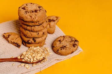 Oatmeal chocolate chip cookies on a kitchen towel on a yellow background with space for text
