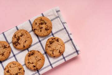 Oatmeal chocolate chip cookies on a checkered towel on a pastel pink background with space for text
