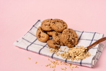 Oatmeal chocolate chip cookies on a checkered towel on a pastel pink background with space for text