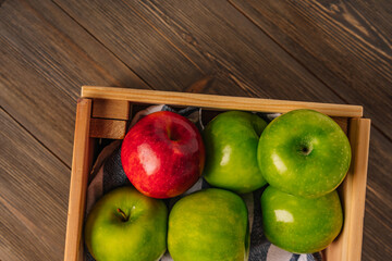 Fresh apples in a wooden box on a wooden table