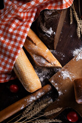 assortiment of tasty fresh  bread. served at  wooden table with cherry tomatos and wheat ears.