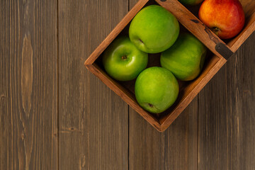 Fresh apples in a wooden box on a wooden table