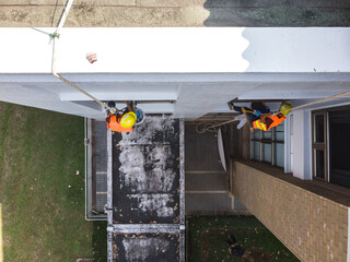 Asian worker cleaning high building windows glass