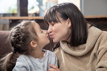 A young mother is kissing her little daughter.
