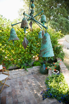 Wind chime or mobile with bronze bells hanging over garden terrace.