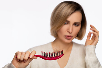 Hair fall problem. Young caucasian woman with comb and problem hair on white background. Beautiful...