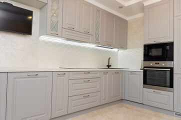 Fototapeta premium Beautiful interior of a classic kitchen in light gray and white colors with led lighting