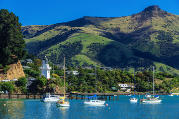 French Bay, Akaroa, New Zealand. The historic lighthouse on the left of the photo first operated in...