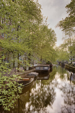 Barges on a city canal with rees in summer foliage.