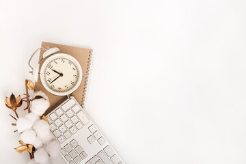 Office background with clock, keyboard and cotton branch on white Desk. Top view with space for text