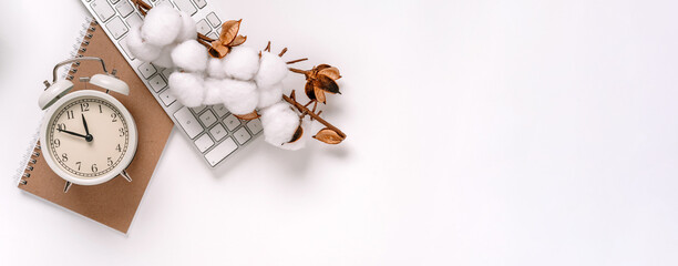 Office background with clock, keyboard and cotton branch on white Desk. Top view with space for text