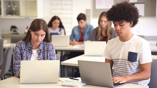 College student using laptop in class during computer lesson. Black high school student studying on laptop in university library with his classmate.