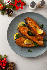 Fried carp in pieces, served on a gray plate. Marbled bright background.