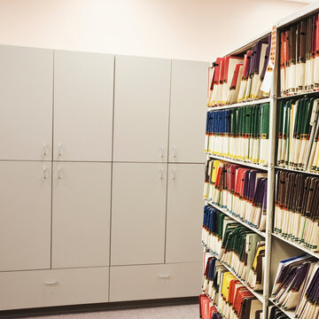 Bookshelves with files and cabinets in office, analogue record storage.