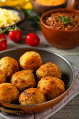 Lentil and millet meatballs. Served on tomato salsa with buckwheat. Gray plate, wooden boards in the background. Front view.
