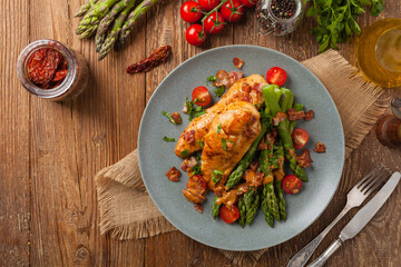 Roasted chicken breast, served on asparagus with tomato sauce, dried tomatoes. Top view.