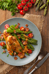 Roasted chicken breast, served on asparagus with tomato sauce, dried tomatoes. Top view.